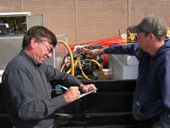 Photo shows an inspector checking equipment used to apply pesticides.