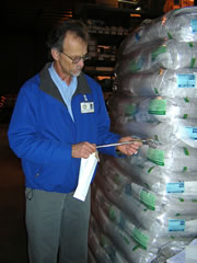 Photo shows an inspector inspecting bags of seeds.