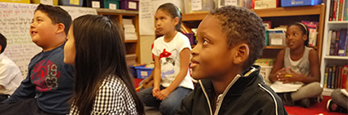 Photograph of children in a daycare setting watching something.