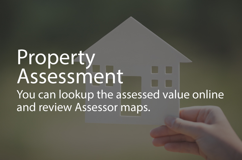 Photo a person holding a house shaped cutout. Caption: Poperty Assssment. You can look up the assessed value online and review Asessor maps.
