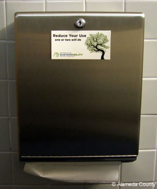 Photo of reduce use sticker on paper towel dispenser.