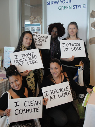 Photo of employees holding signs stating green behaviors at work.