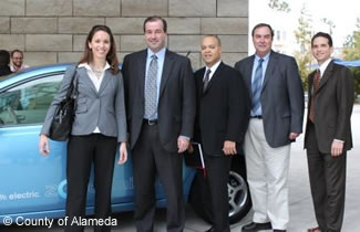 Photo of fleet managers next to an electric vehicle.